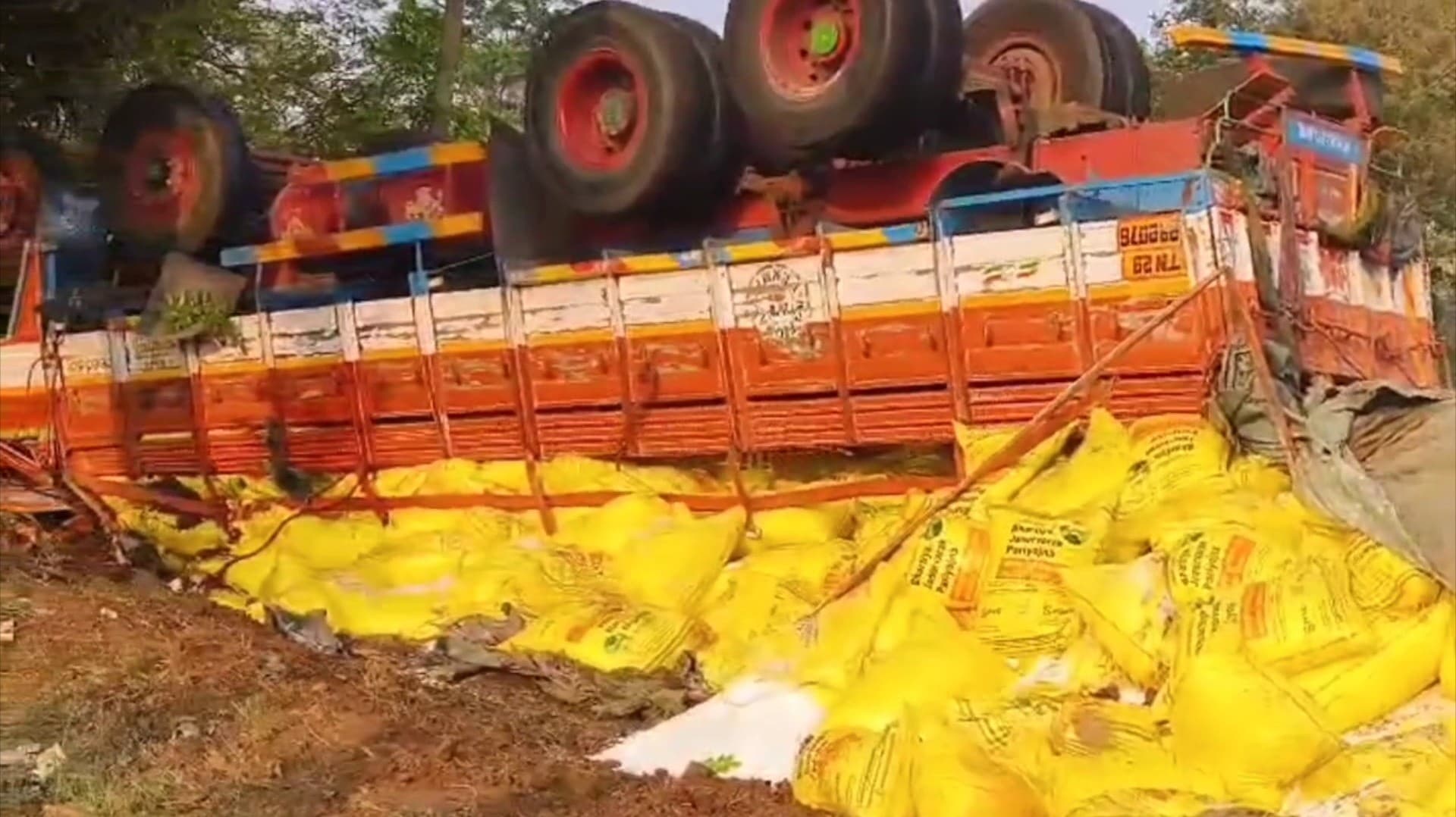 சாலை வளைவில் திரும்பிய போது கவிழ்ந்த லாரி... 5 டன் உர மூட்டைகள் சாலையோரம் விழுந்தன